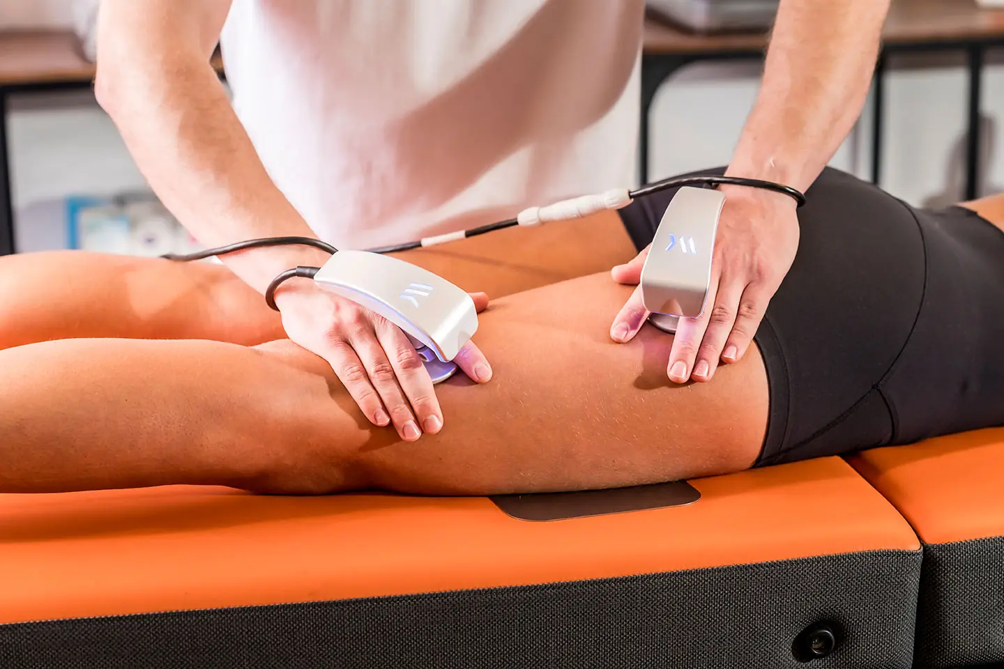 Two Winback handpieces treating a hamstring with the return plate on the table